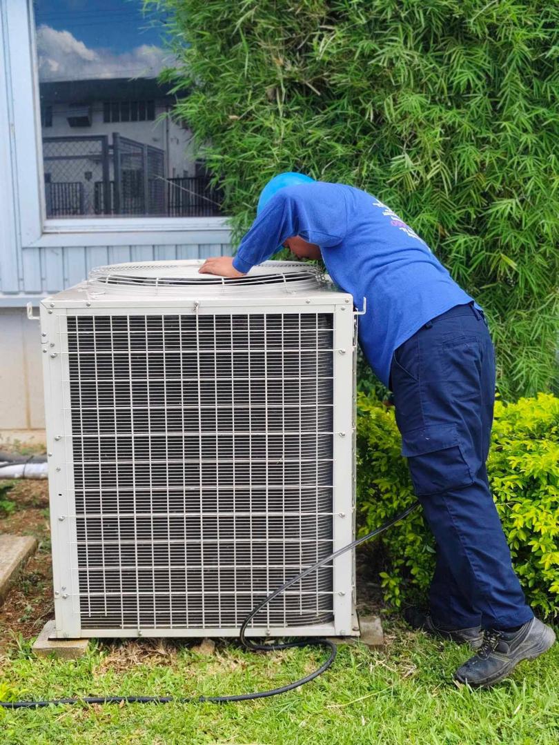 Jakintech technician servicing an outdoor condenser unit